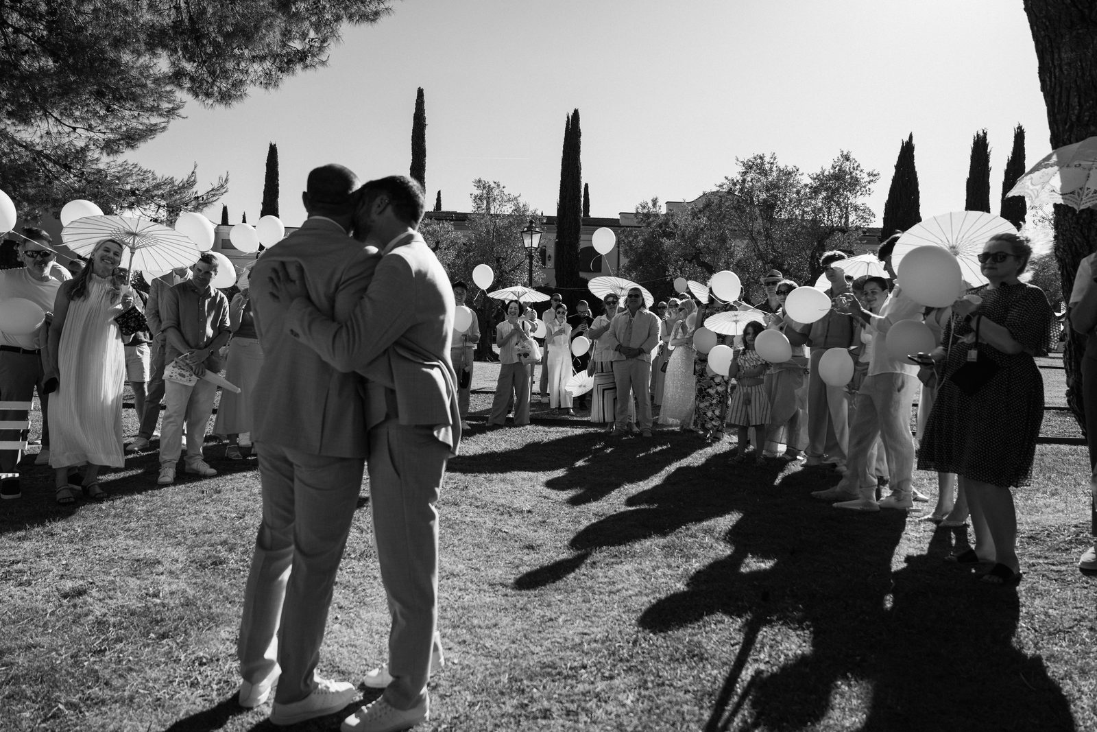 Il sì degli sposi circondati dagli invitati con ombrellini e palloncini, matrimonio in Toscana in bianco e nero