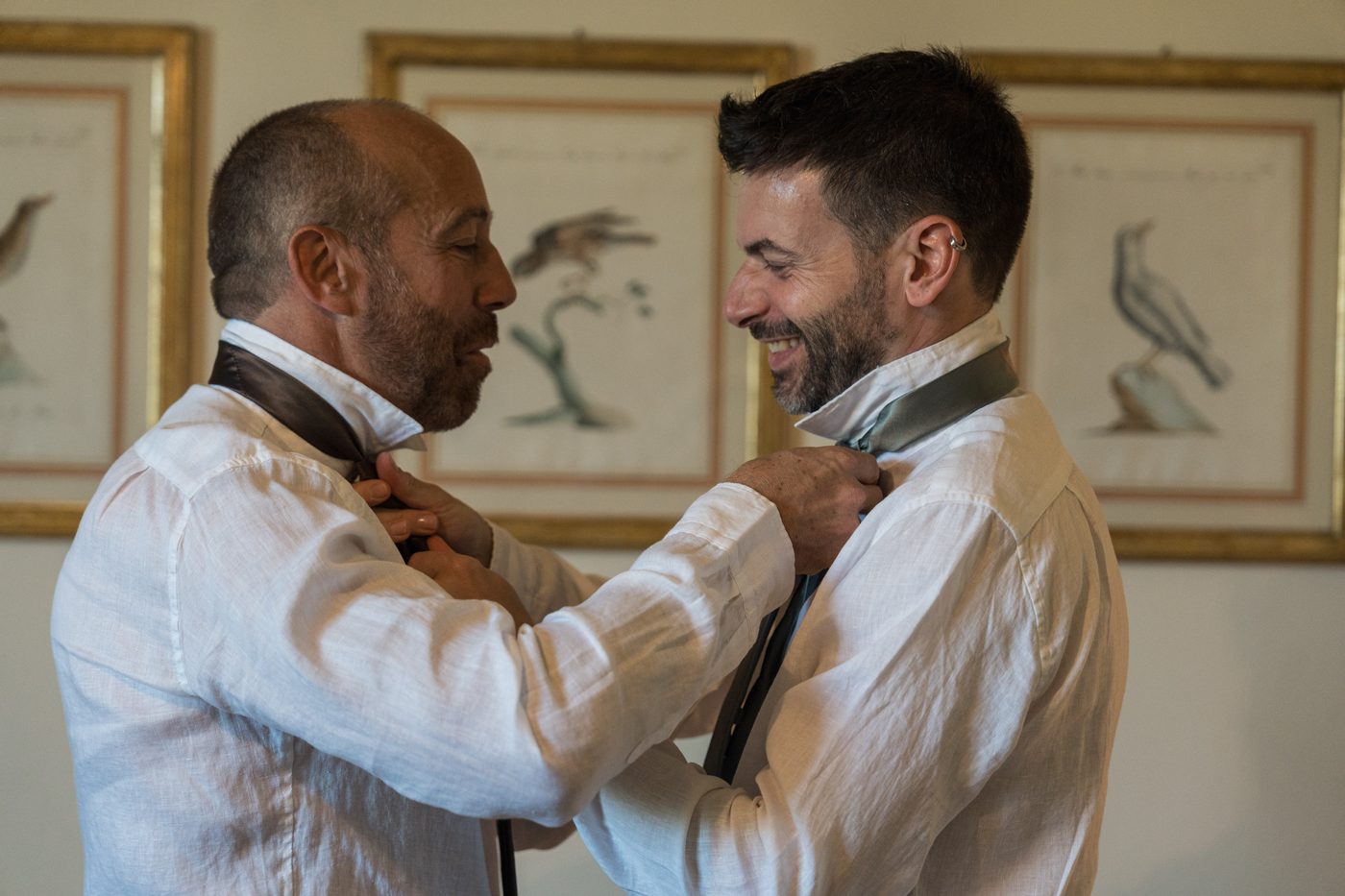 Preparativi dello sposo, la cravatta sistemata da un amico — fotografo matrimonio Toscana ØLAB